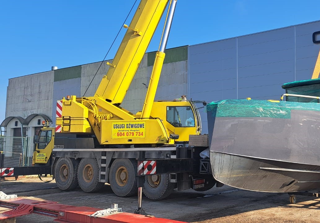 Dźwig samojezdny Liebherr podczas montażu konstrukcji stalowej na tle błękitnego nieba